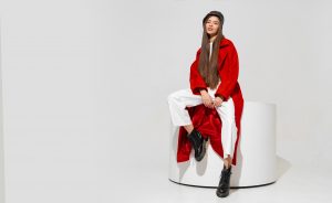 Fashion studio photo of stylish european brunette woman in red coat and black hat posing on white background.  Trendy winter accsesorises.